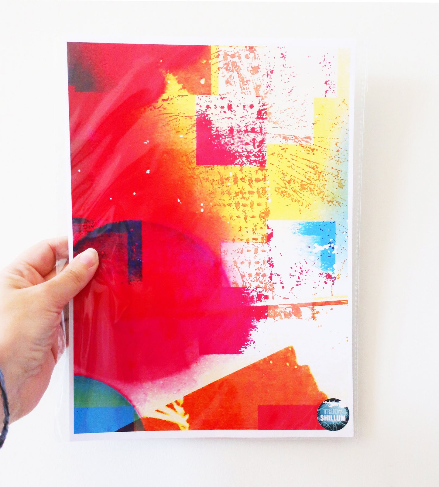 Colorful abstract art print  held by a hand on a white background