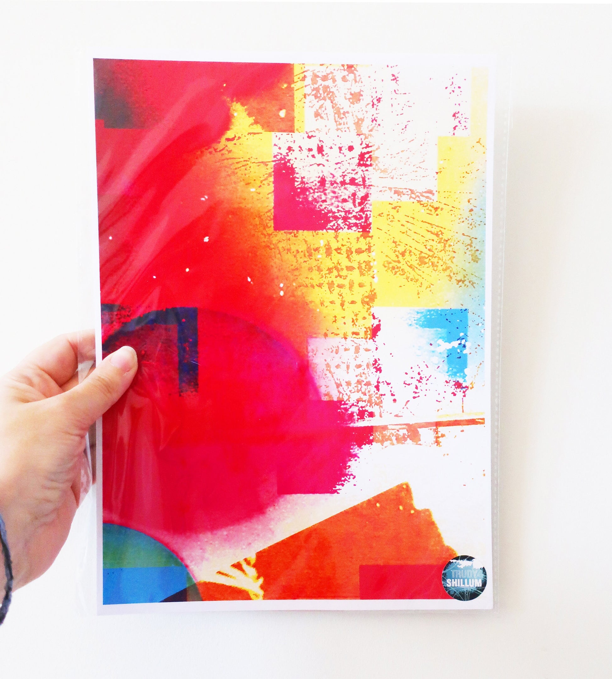 Colorful abstract art print  held by a hand on a white background