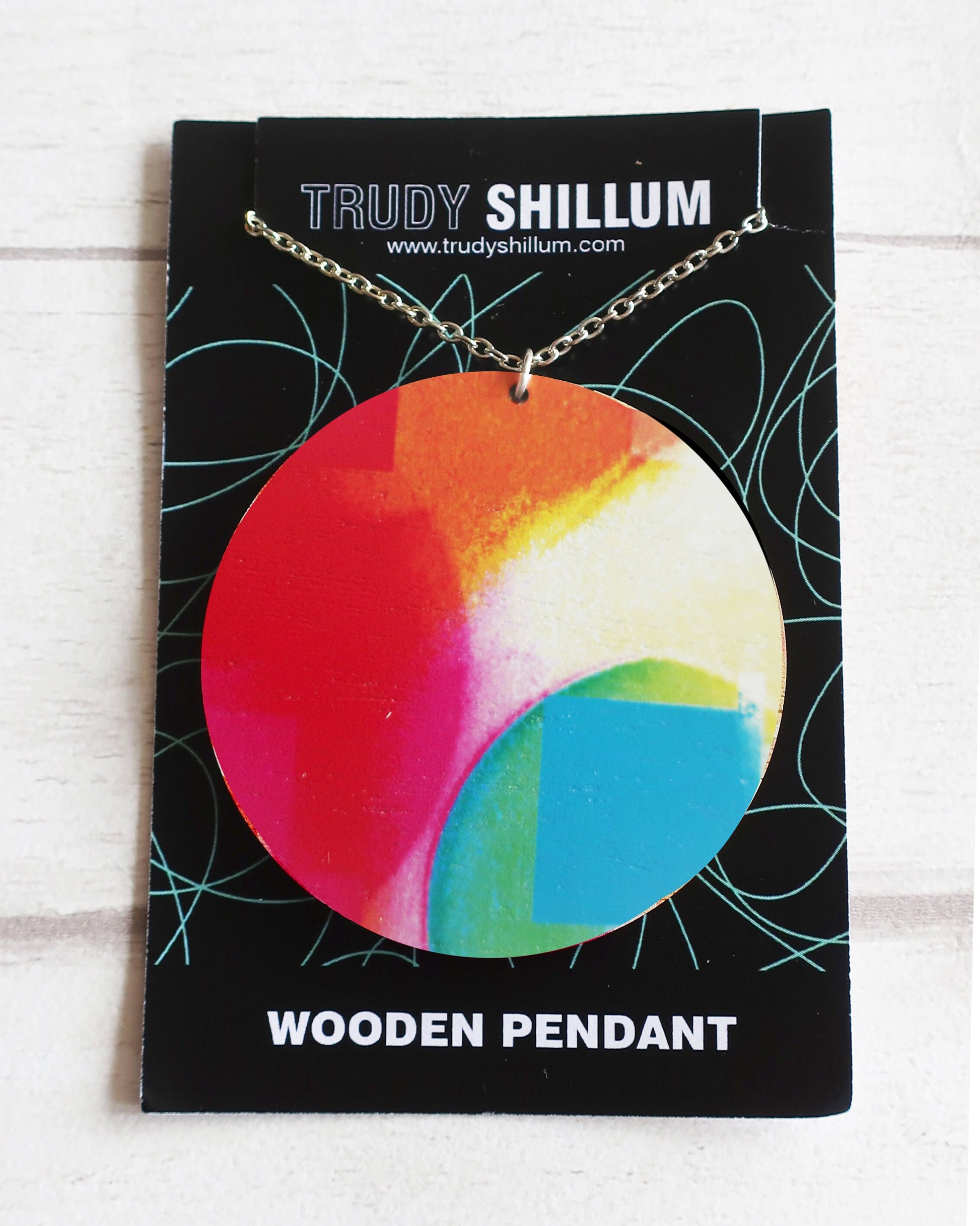 Colorful wooden pendant on a Trudy Shillum branded card
