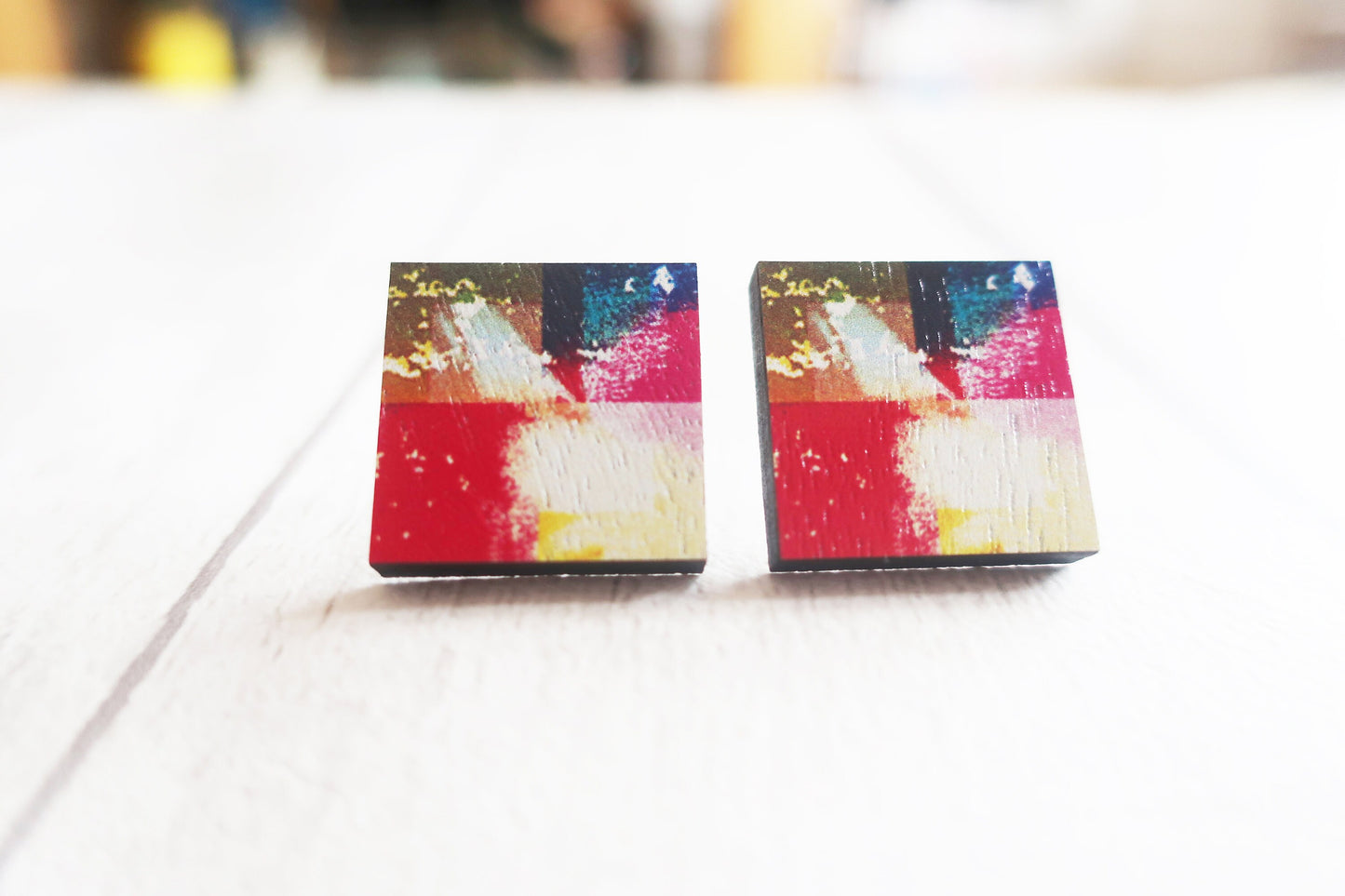 Colorful abstract square earrings on a white surface