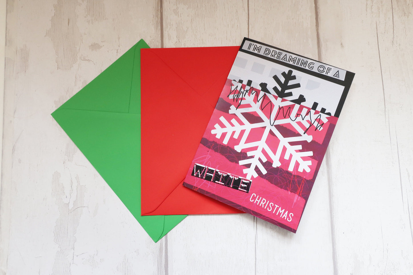 Christmas card with snowflake design and two envelopes on a wooden surface