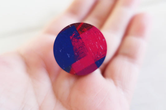 Round red and blue ring held in a hand against a white background