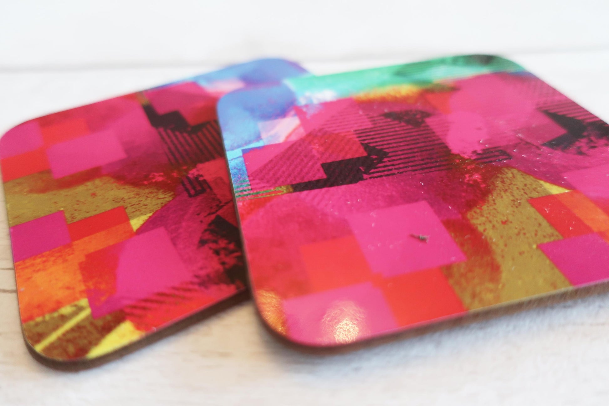 Two colorful coasters with geometric patterns on a white surface