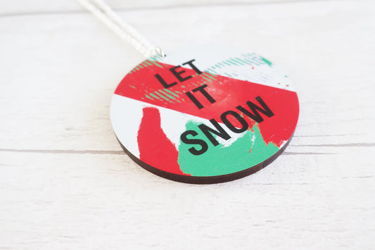 Round decorative necklace with 'Let It Snow' text on a white background