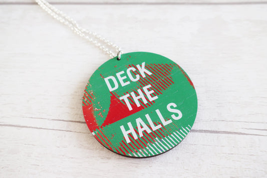 Decorative necklace with 'Deck the Halls' text on a white wooden surface