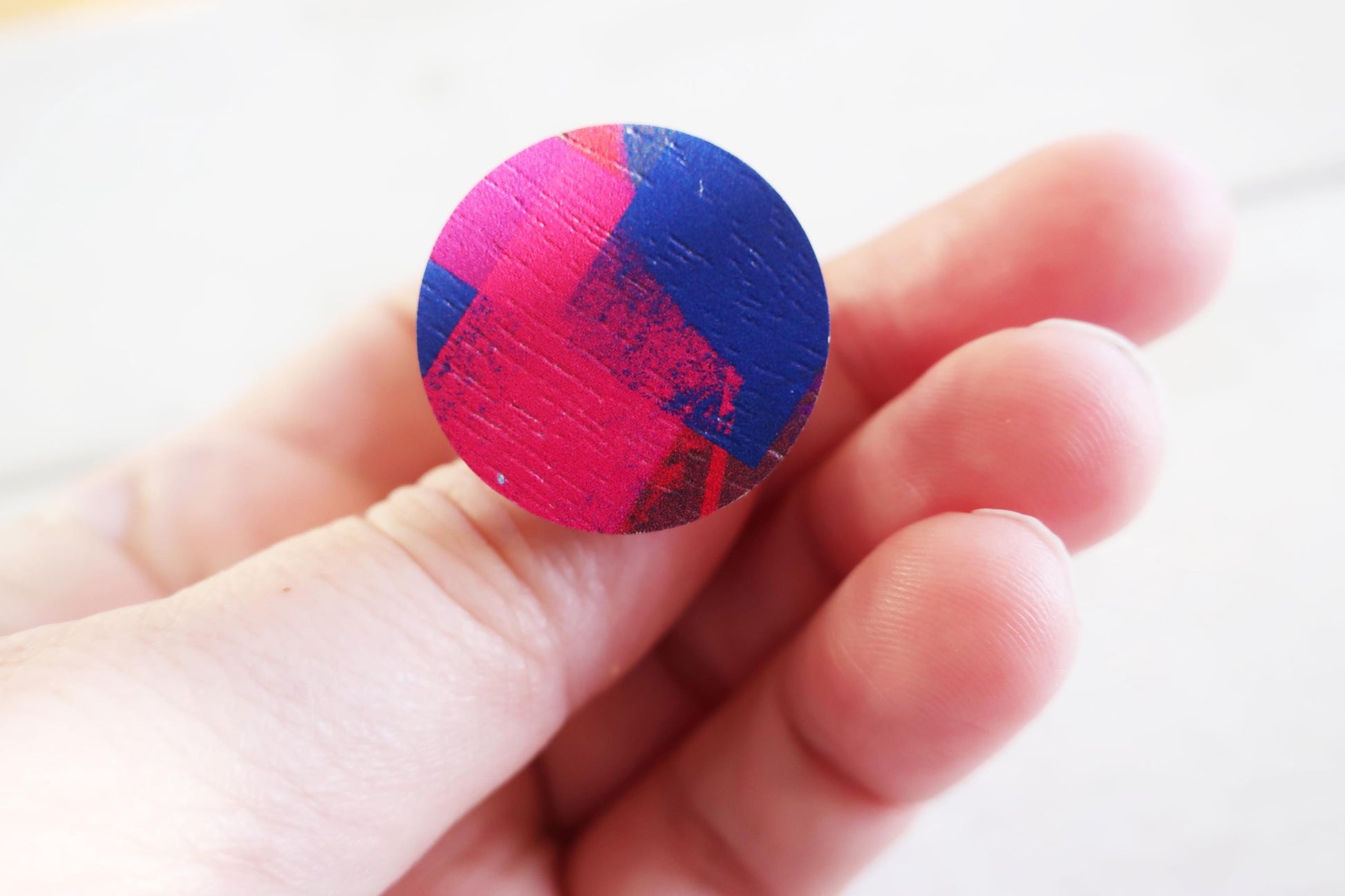 Colorful circular ring held between fingers on a white background
