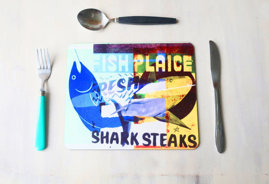 Colorful placemat with fish design and text, surrounded by cutlery on a white surface.
