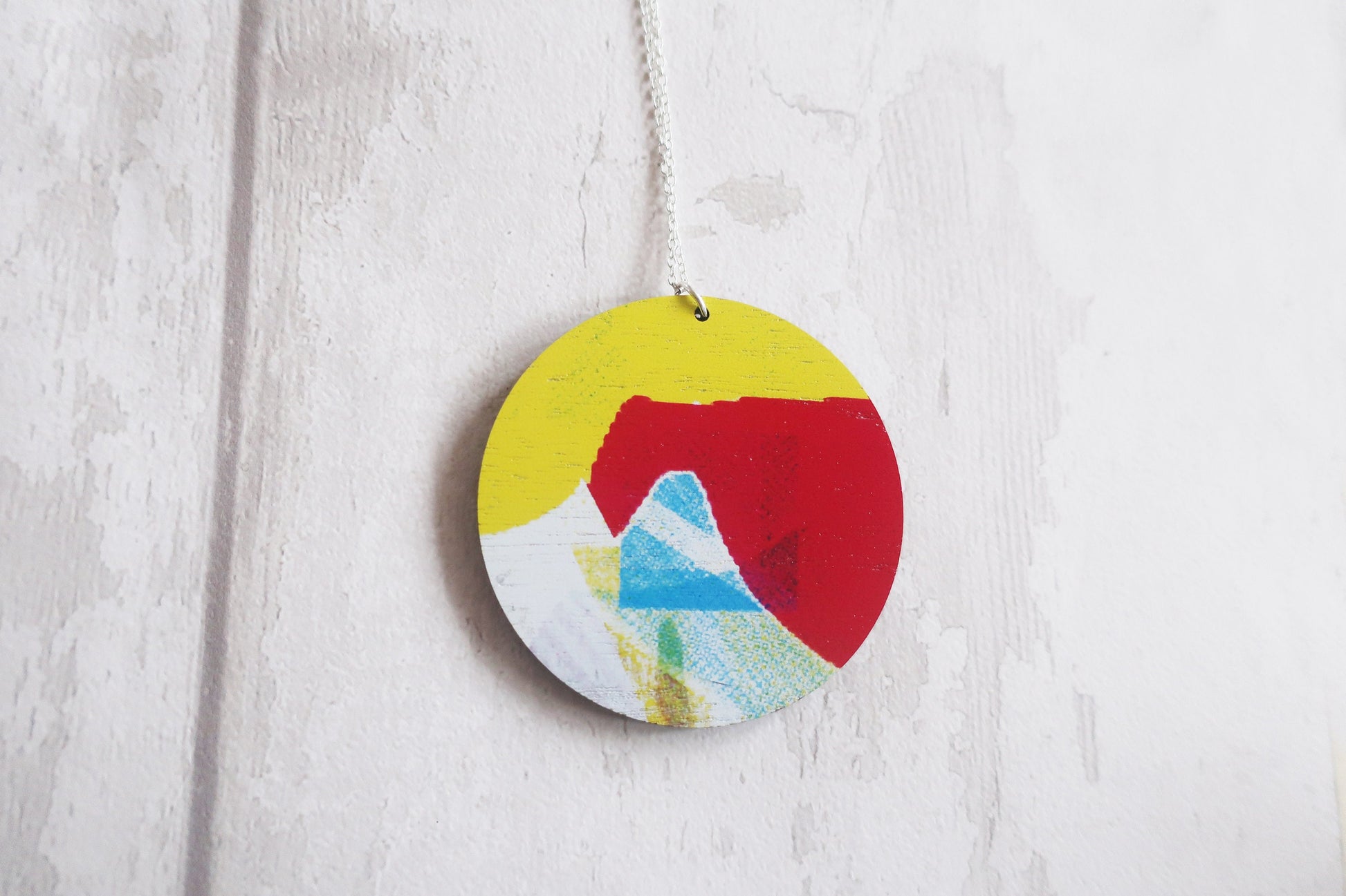 Round colorful pendant with abstract design on a white wooden background