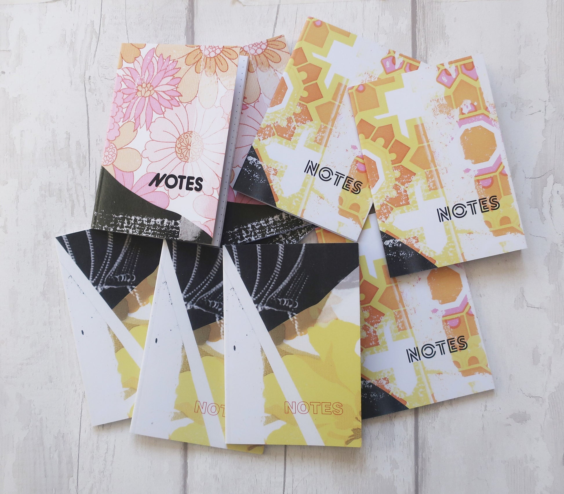 Colorful notebooks with floral and abstract designs on a wooden surface