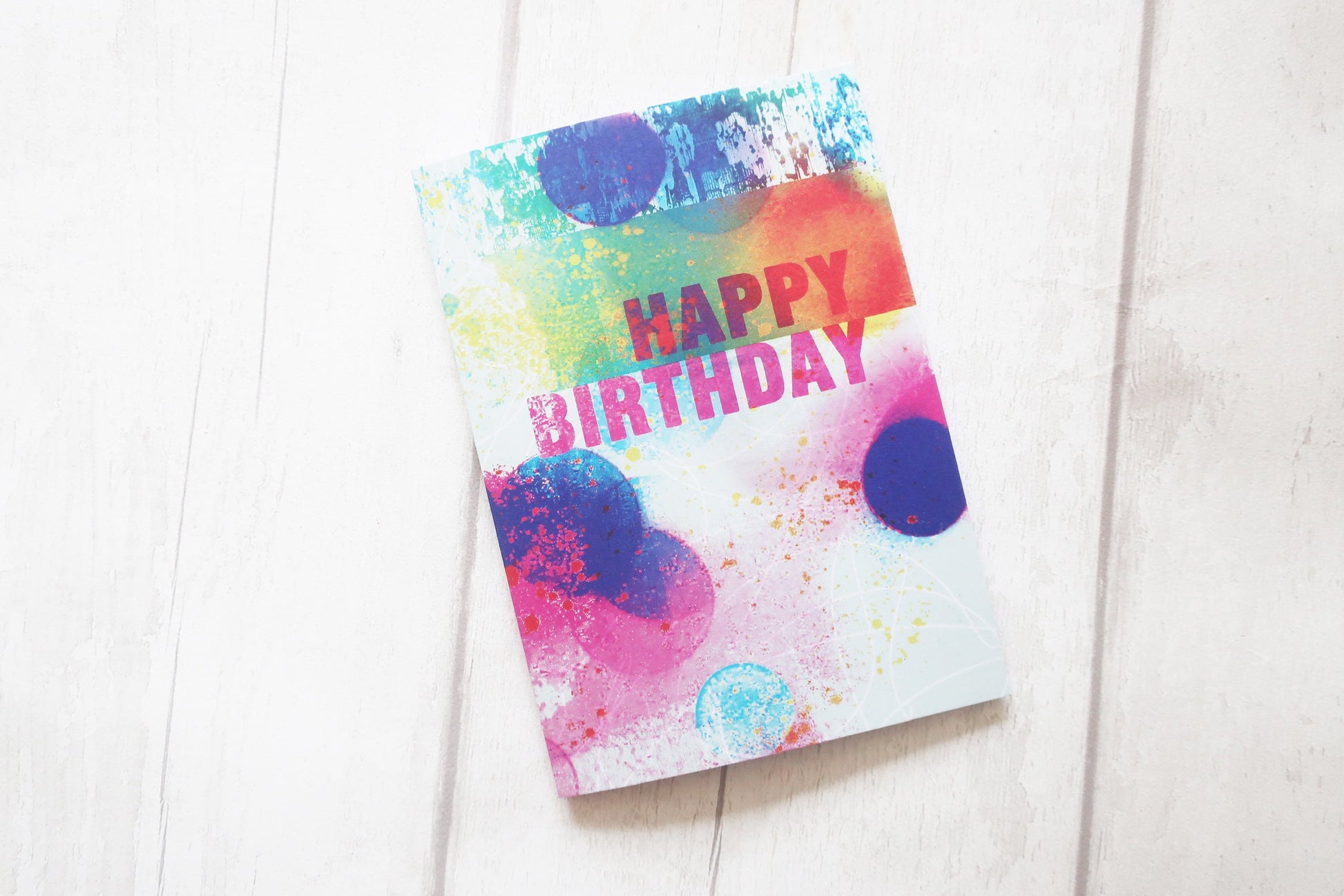 Colorful 'Happy Birthday' card on a white wooden surface