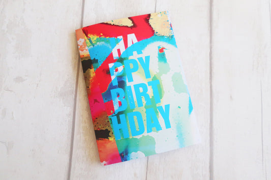 Colorful birthday card with watercolor design on a white wooden surface