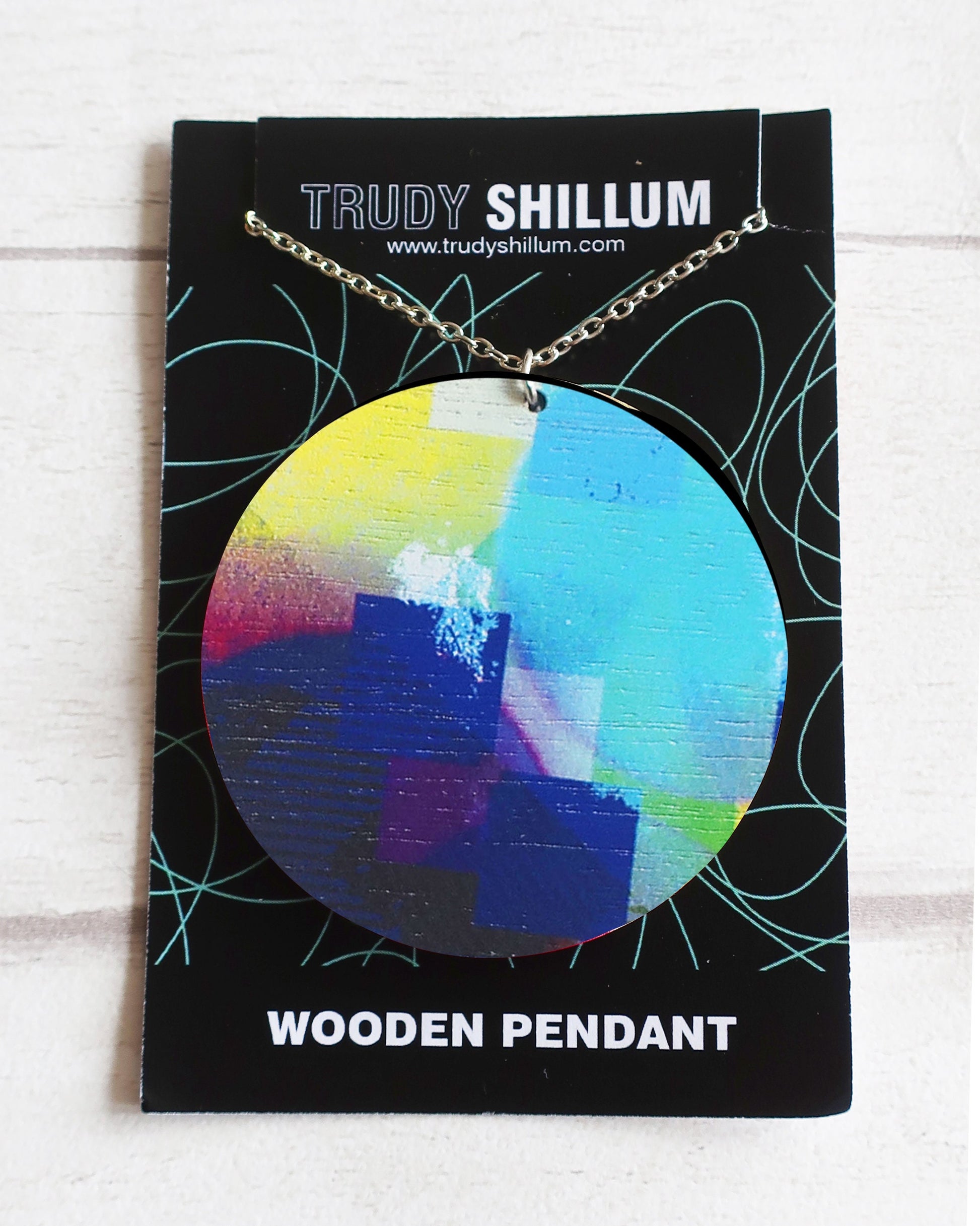 Trudy Shillum wooden pendant necklace on a branded card with a colorful pendant.