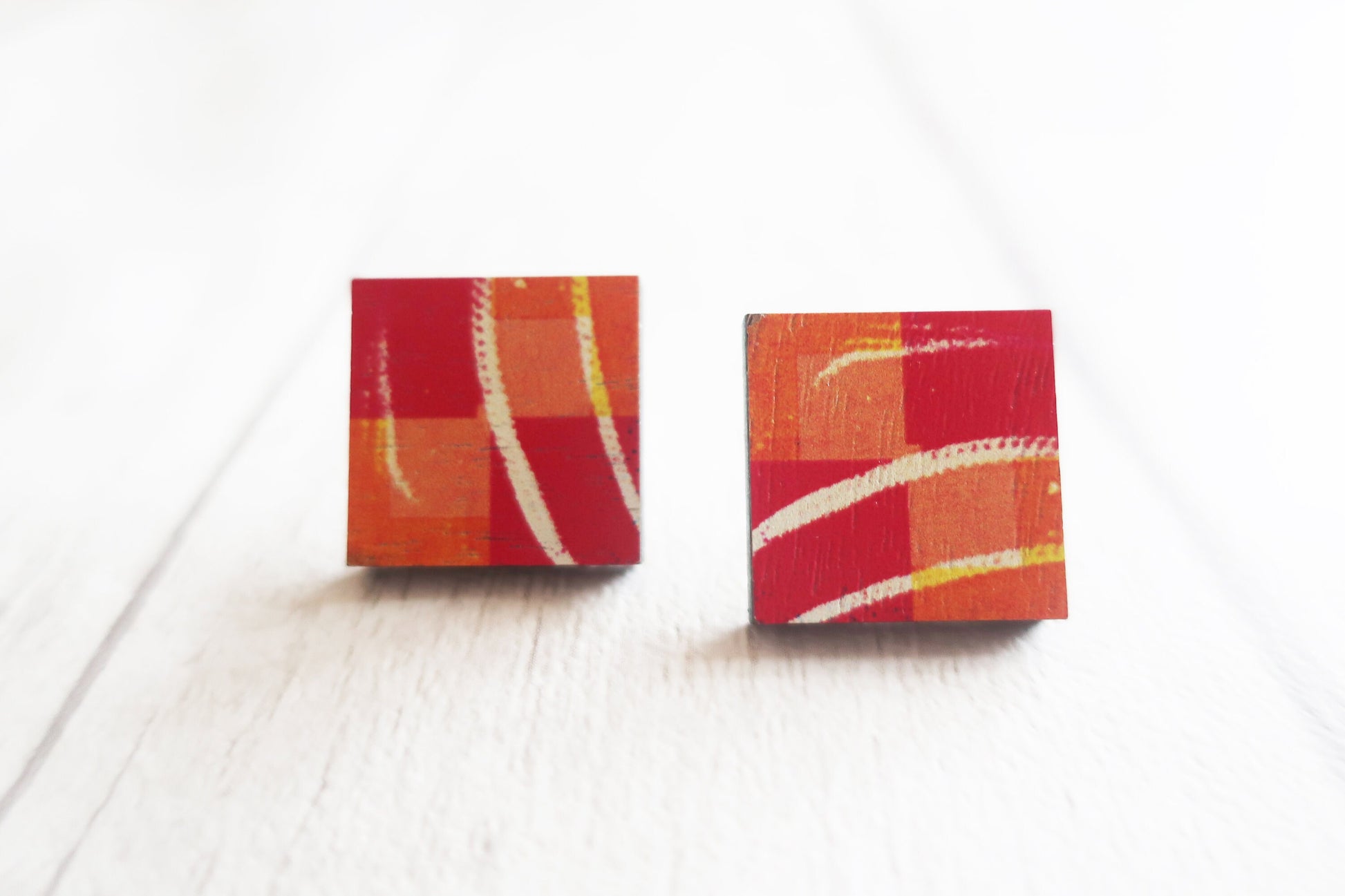 Square earrings with red and orange design on a white background