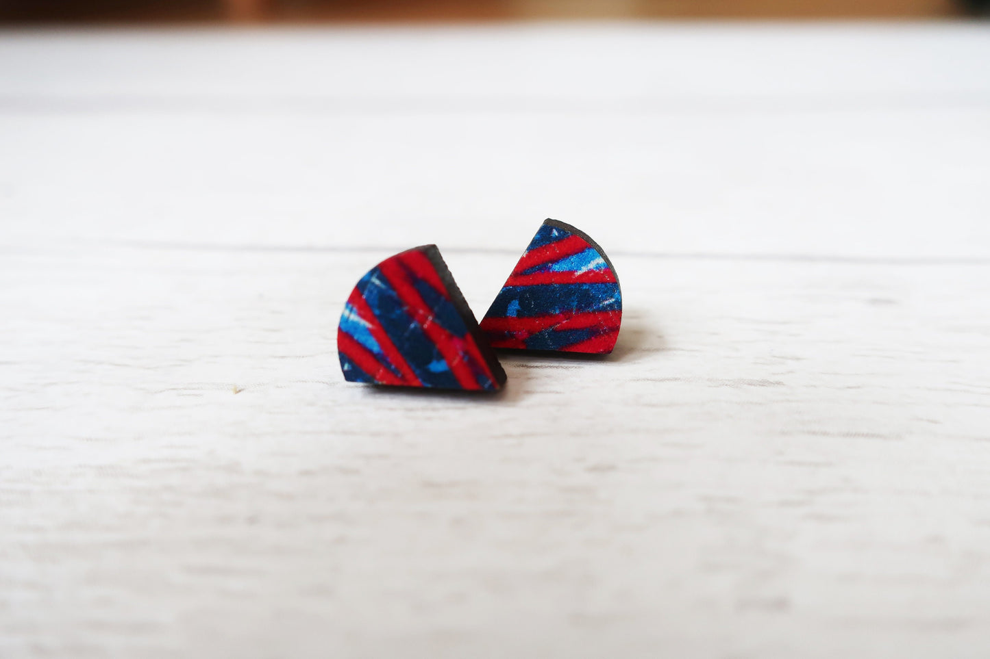 Pair of red and blue striped triangle earrings on a white surface