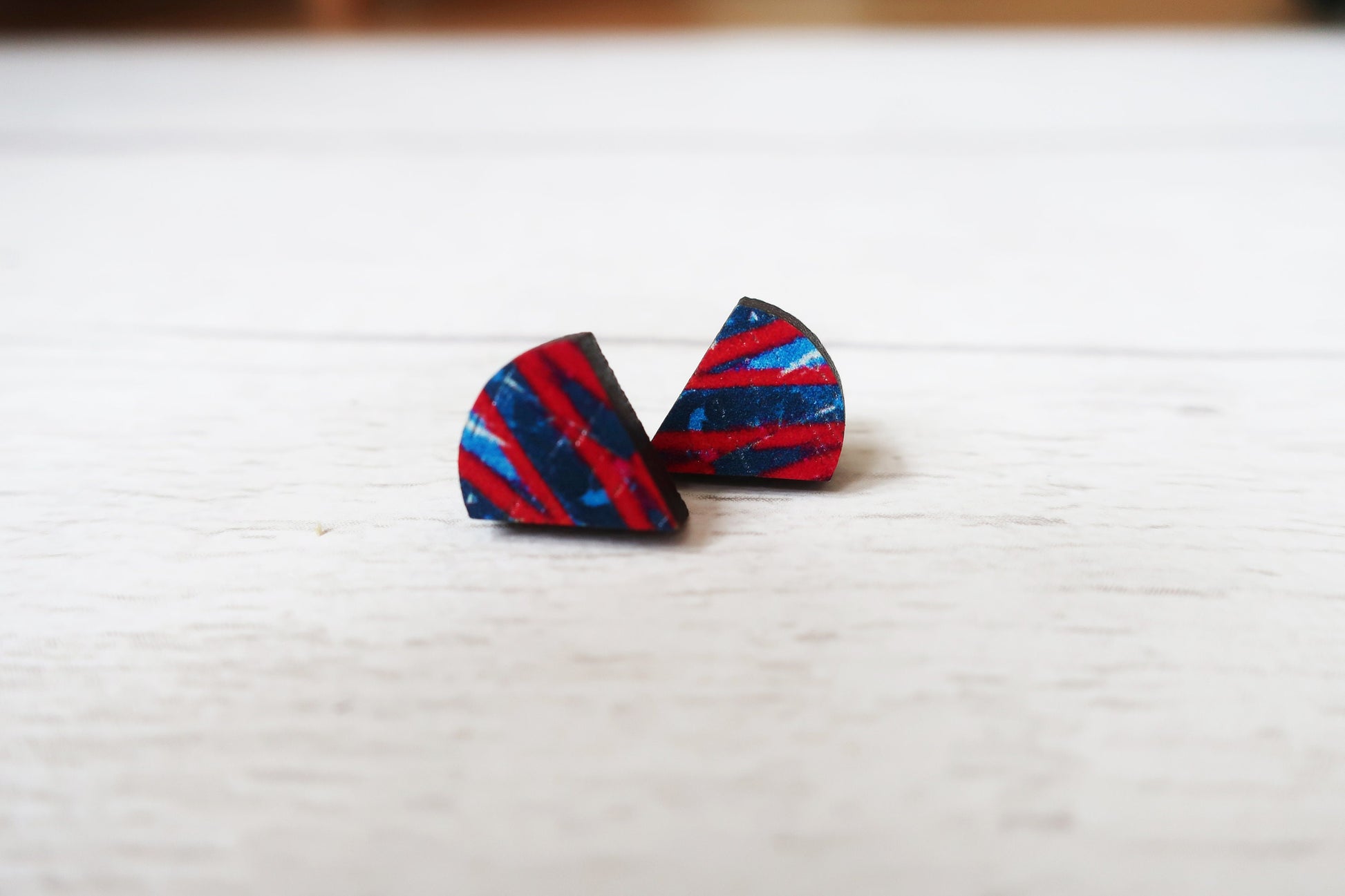Pair of red and blue striped triangle earrings on a white surface