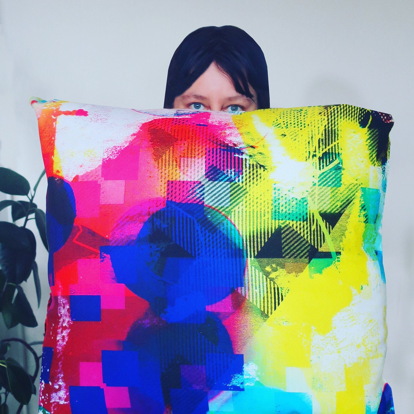 Person holding a colorful abstract-patterned pillow against a white background