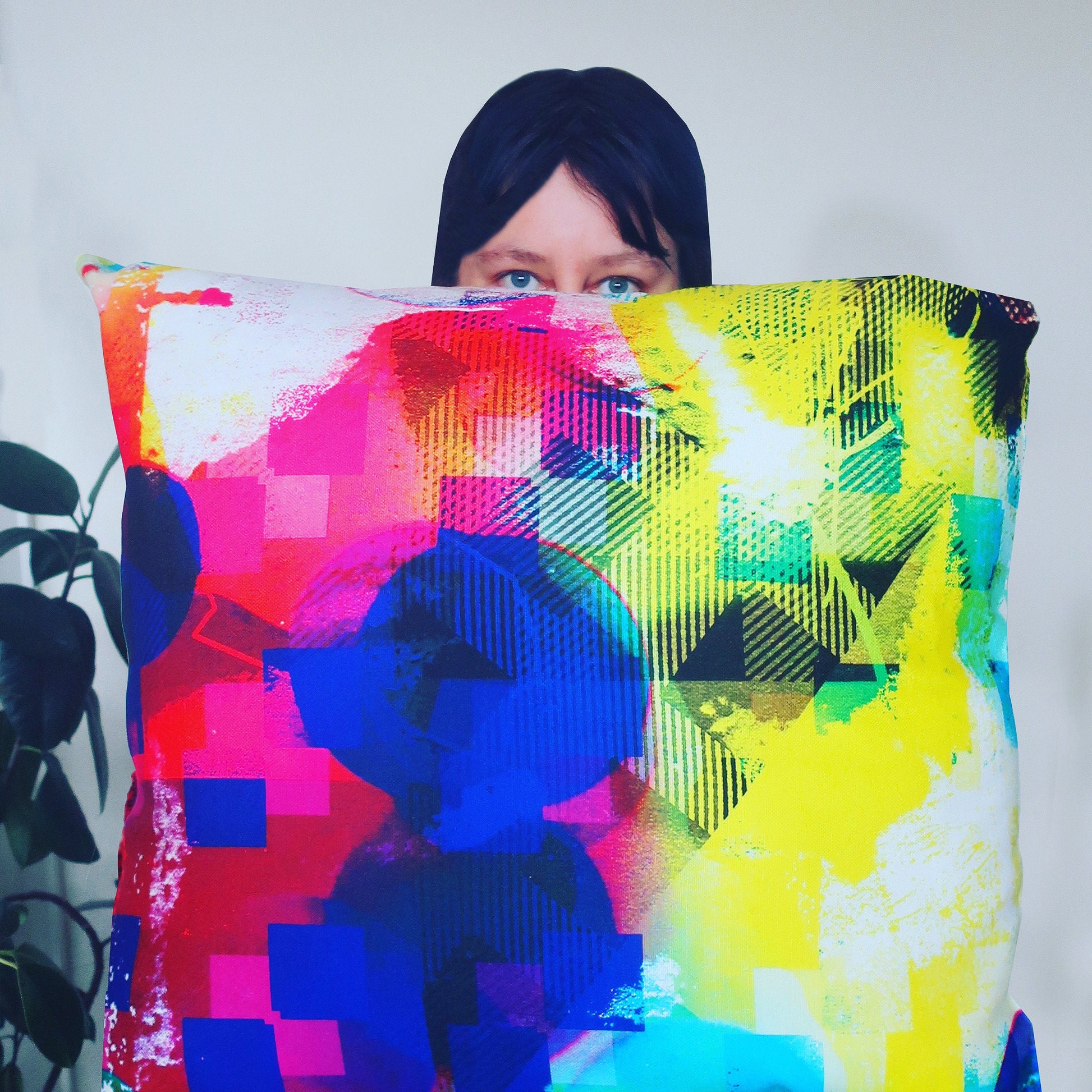 Person holding a colorful abstract-patterned pillow against a white background