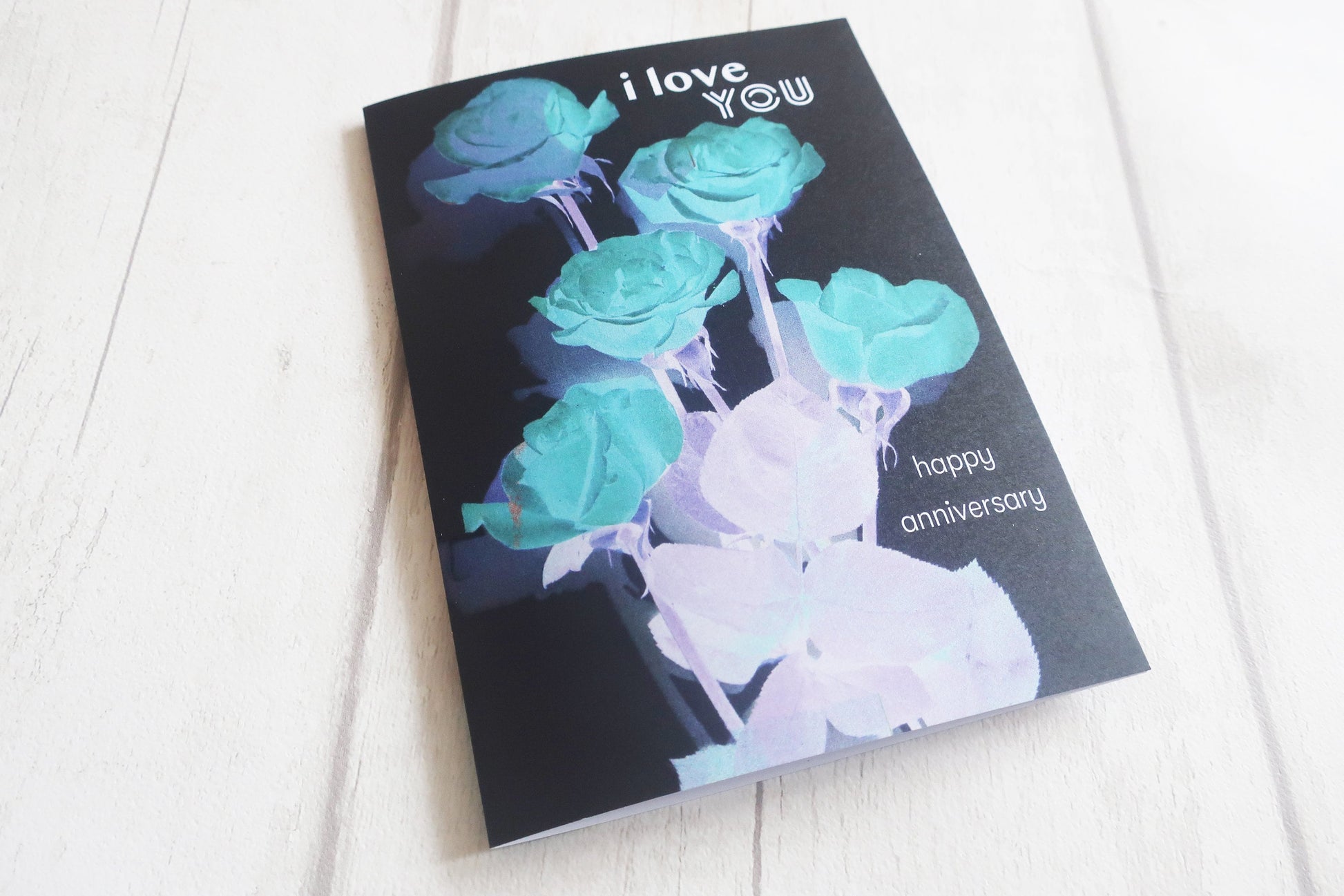 Greeting card with teal and white flowers and 'I love you' text on a black background