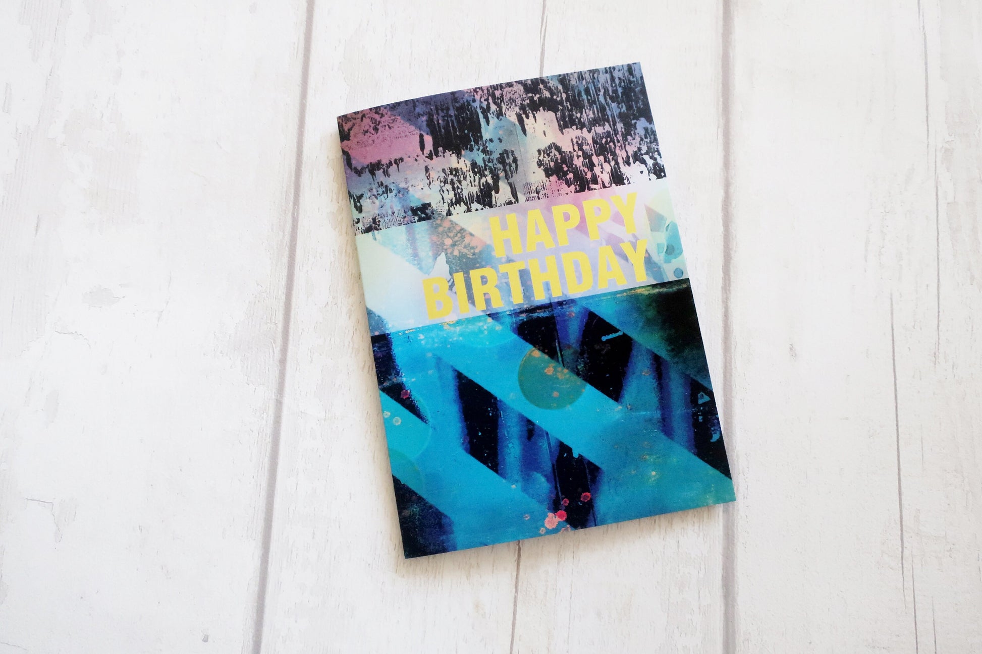 Colorful birthday card with abstract design on a white wooden surface