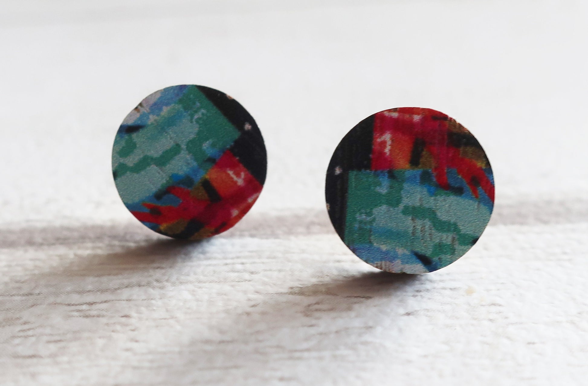 Colorful round earrings on a light wooden surface