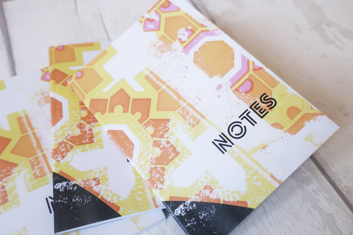 Notebook with geometric pattern and 'NOTES' text on a light wooden surface