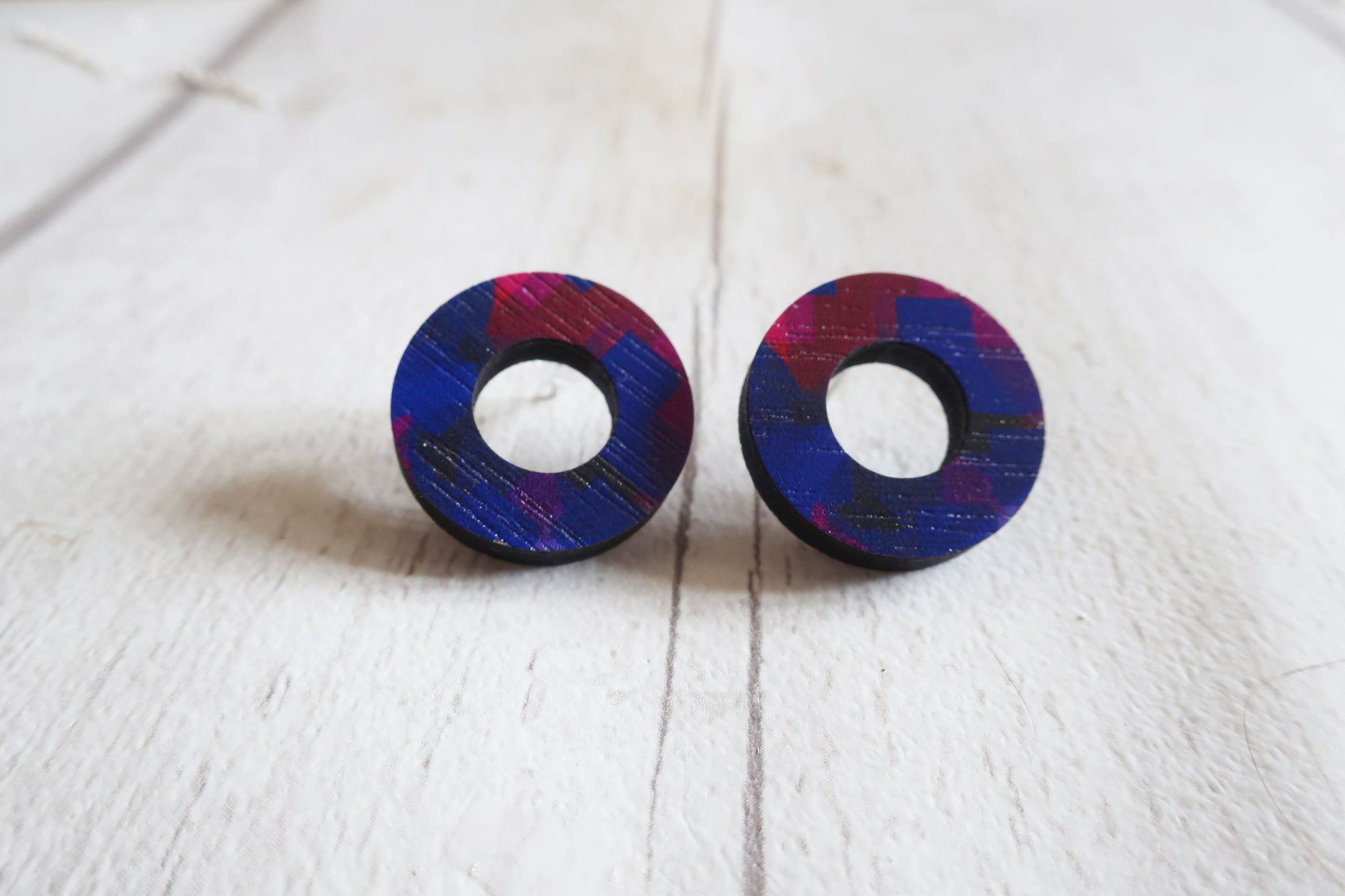 Pair of round earrings with a blue and pink design on a white surface