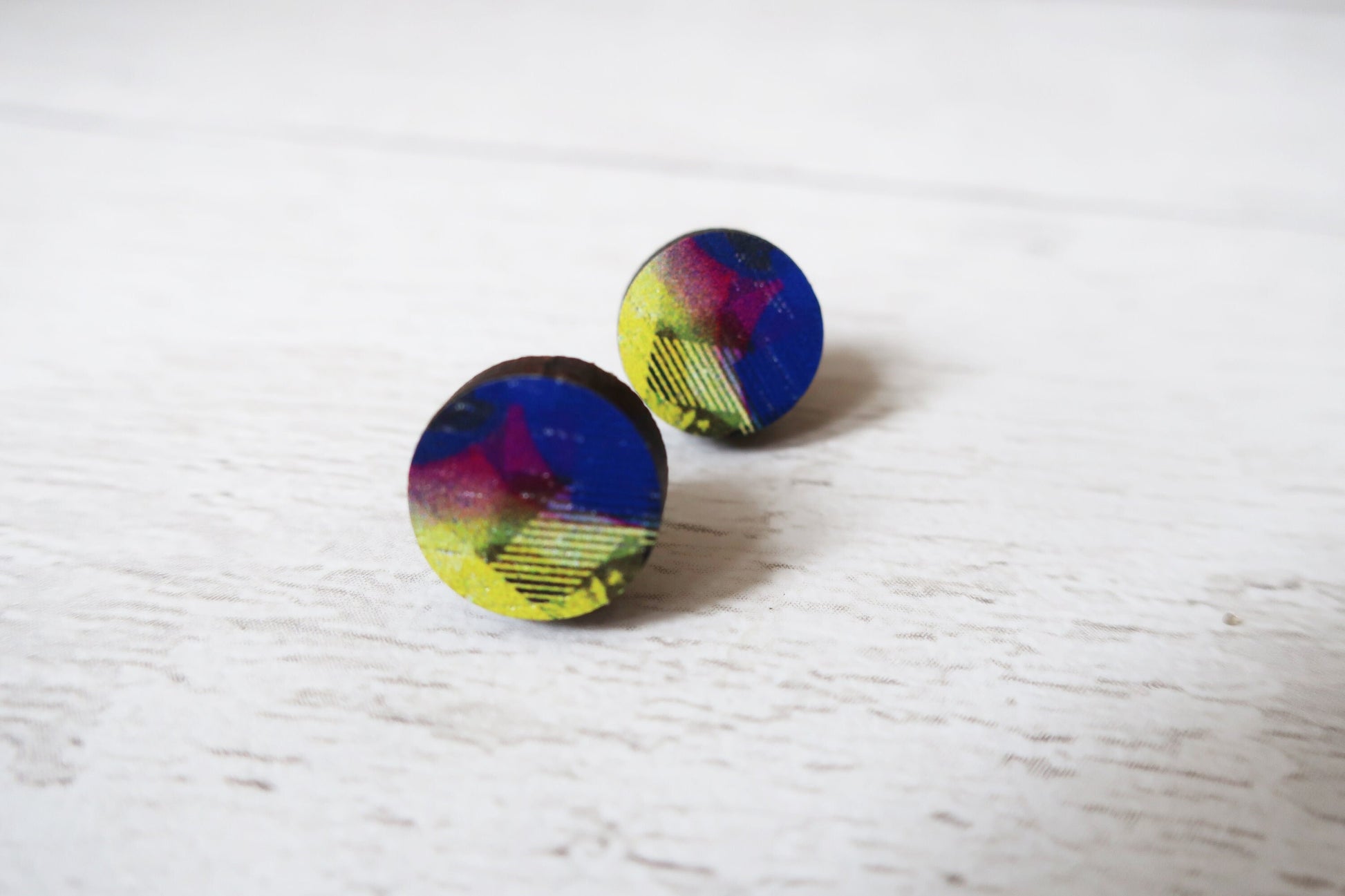 Multicolored round earrings on a light wooden surface