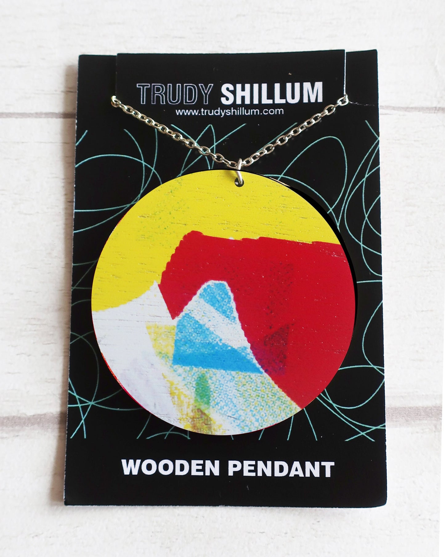 Wooden pendant on a Trudy Shillum branded card with a colorful design.
