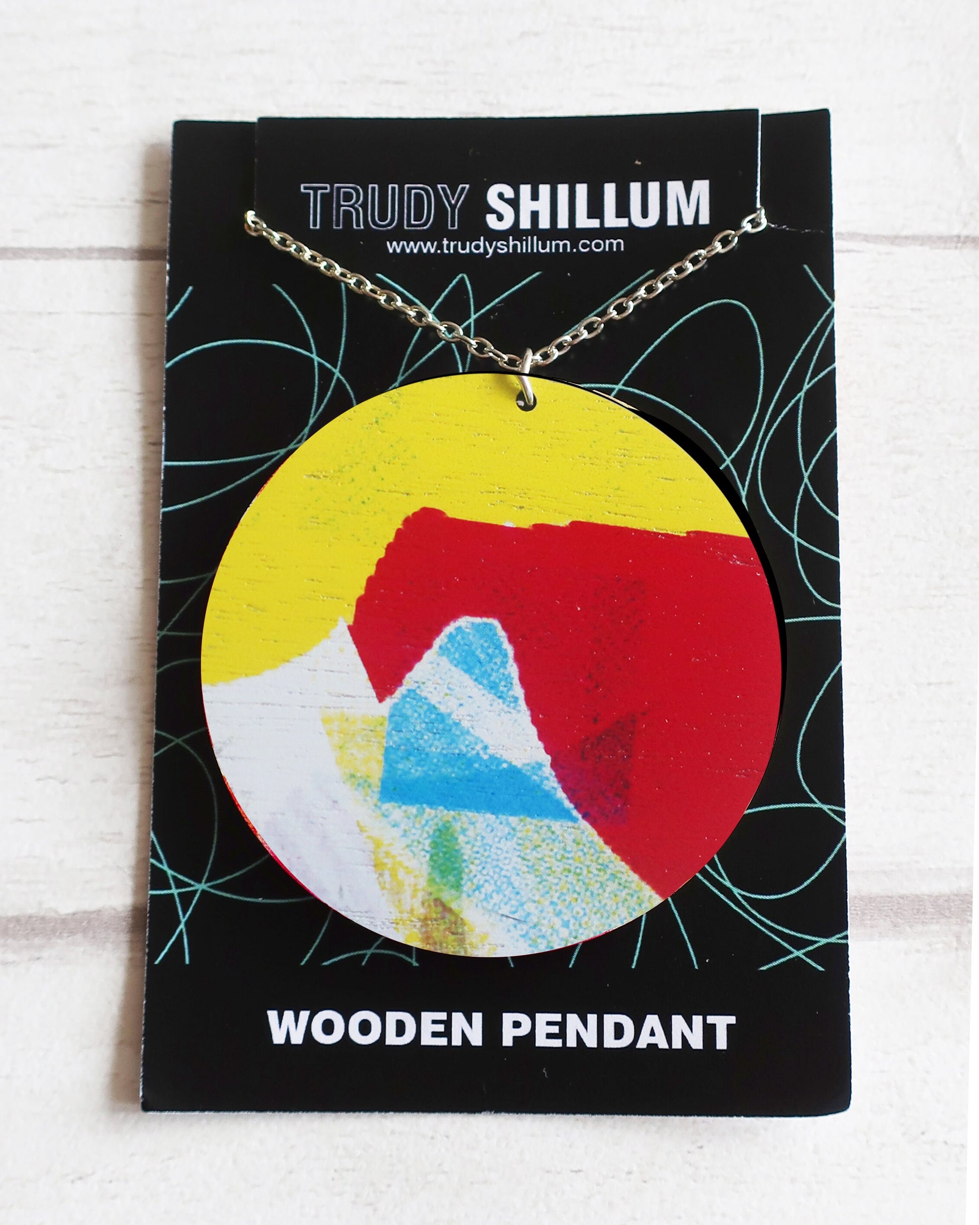 Wooden pendant on a Trudy Shillum branded card with a colorful design.