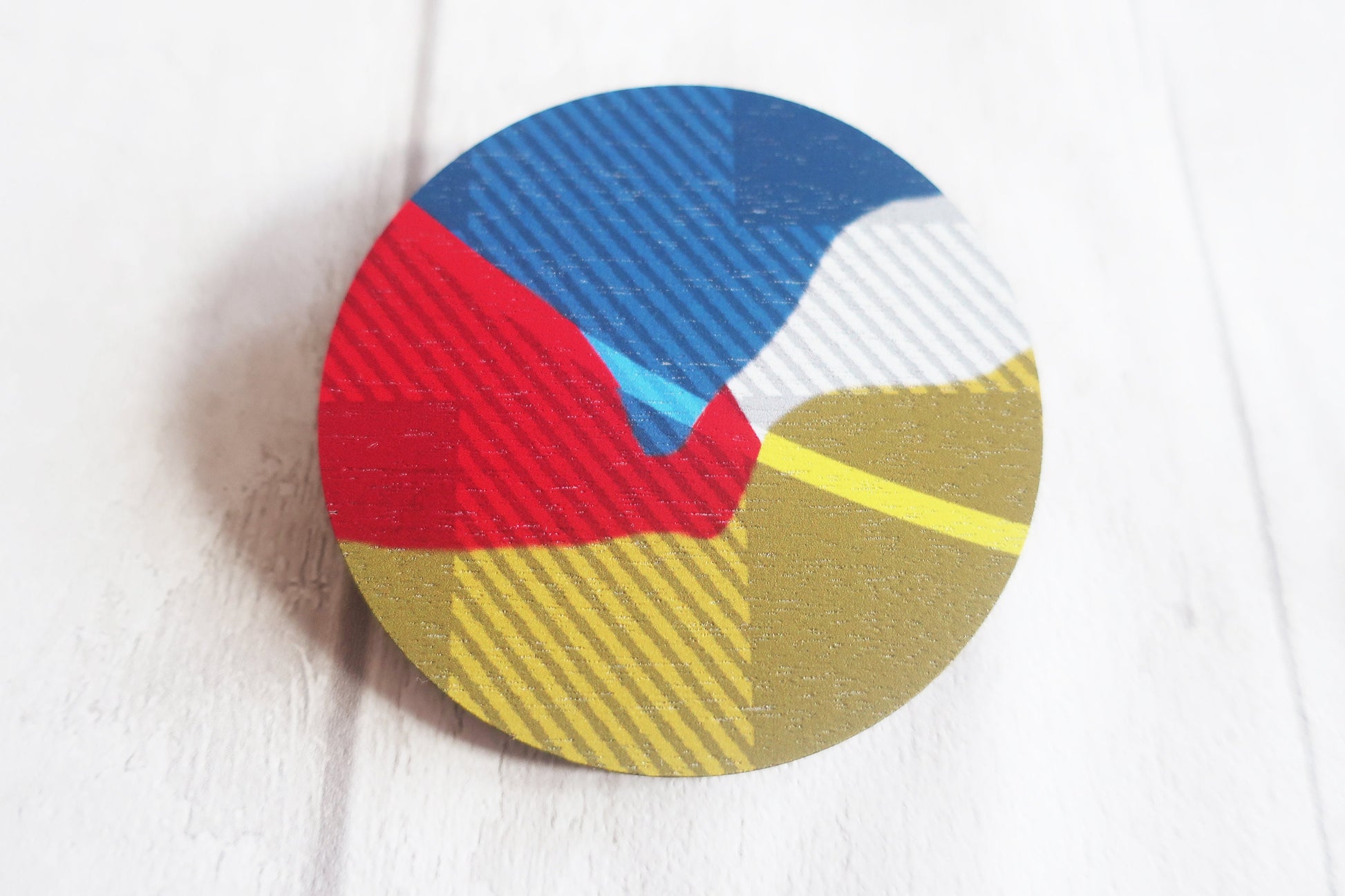 Round brooch with colorful geometric pattern on a white surface