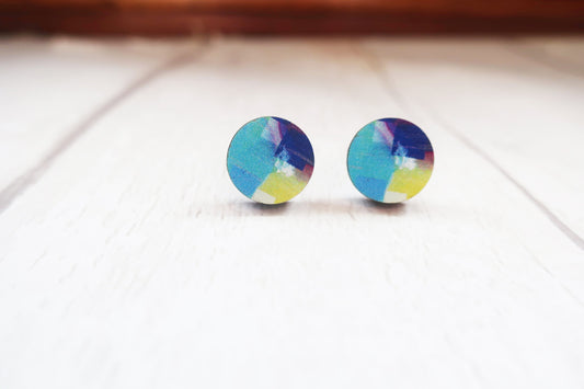 Colorful round earrings on a light wooden surface