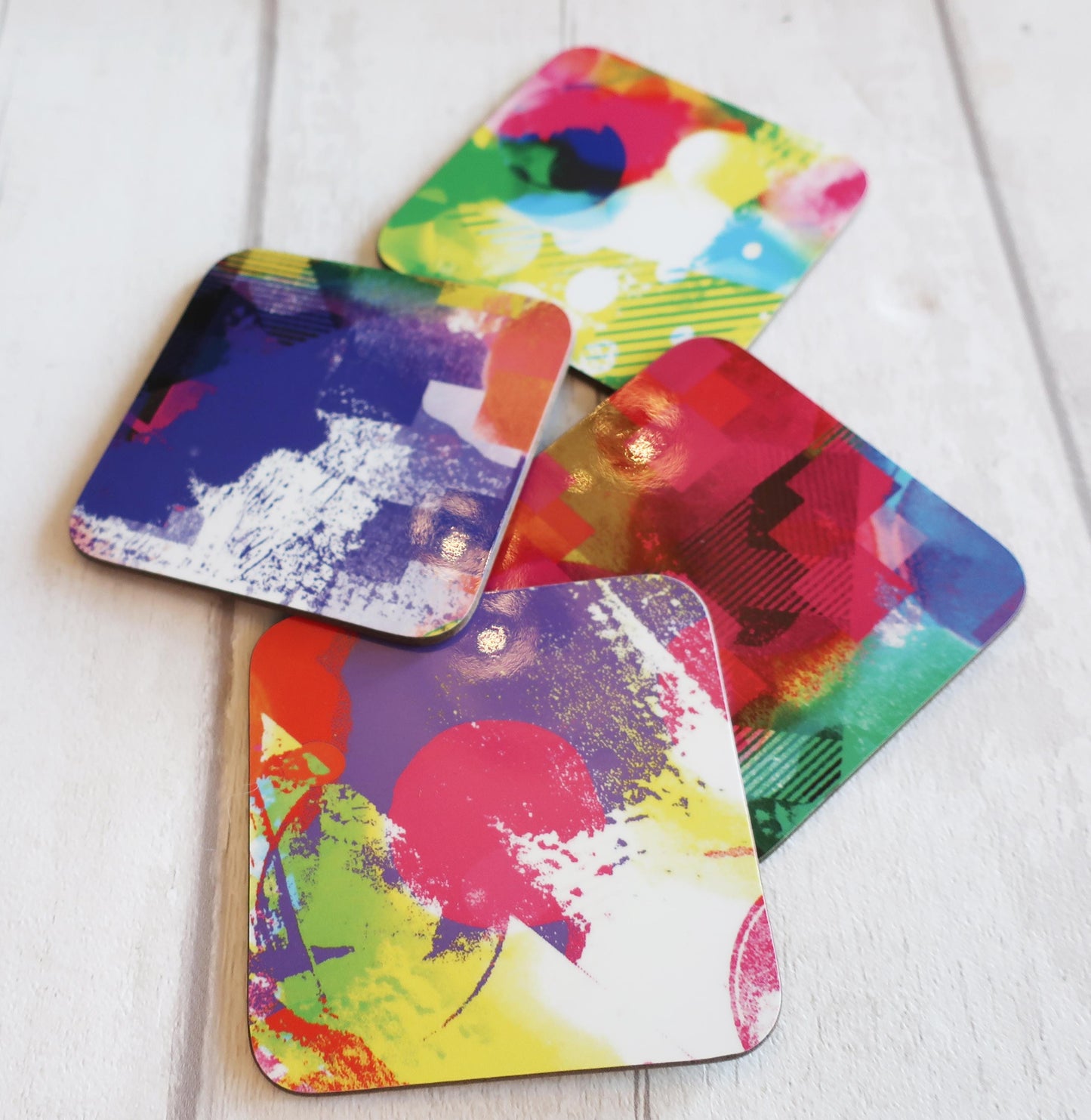 Set of colorful abstract coasters on a white wooden surface