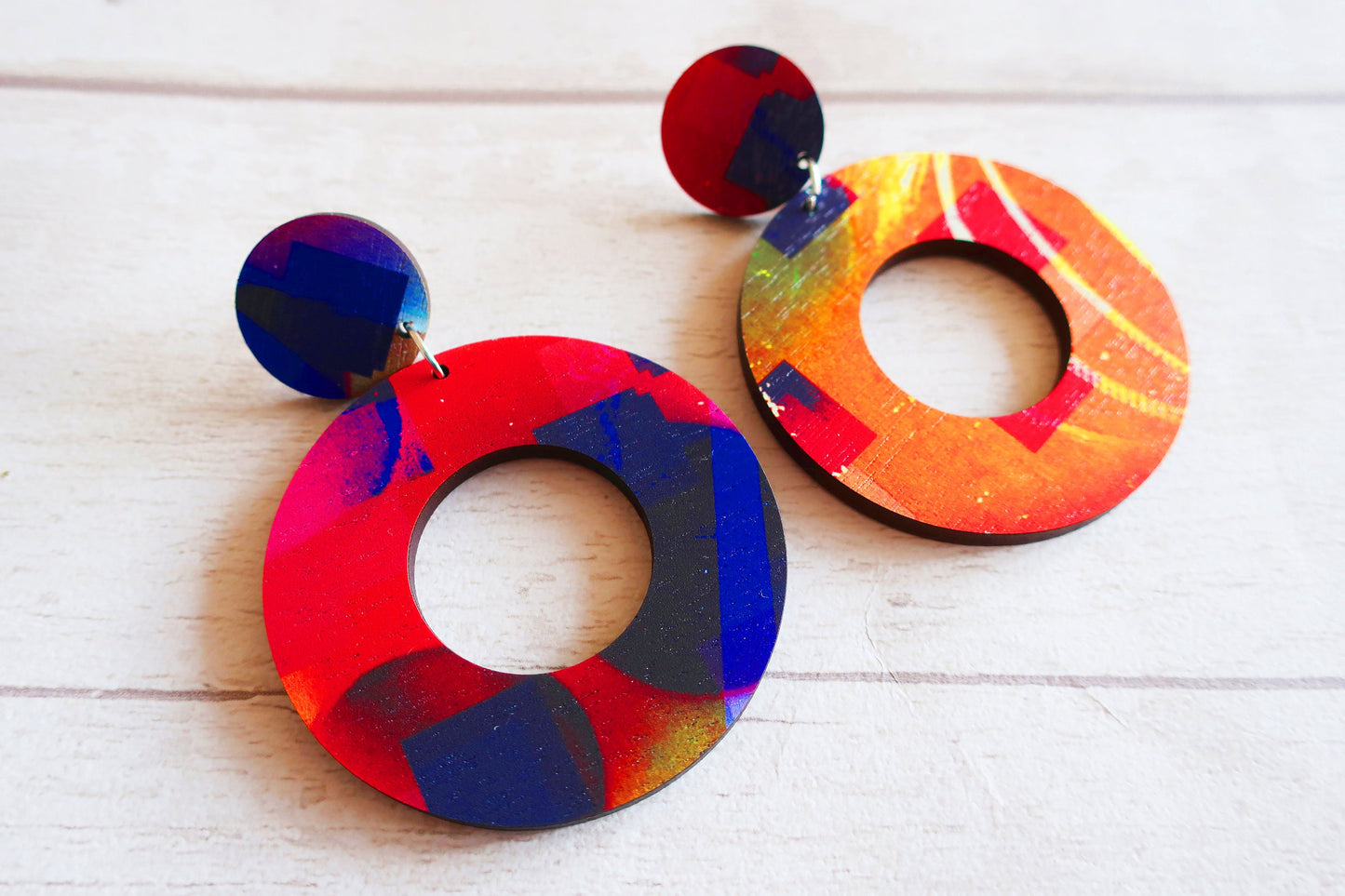Colorful round earrings on a light wooden surface