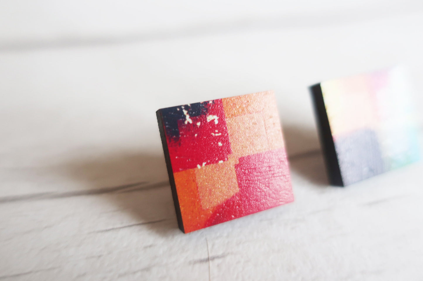 Colorful square earrings on a light surface
