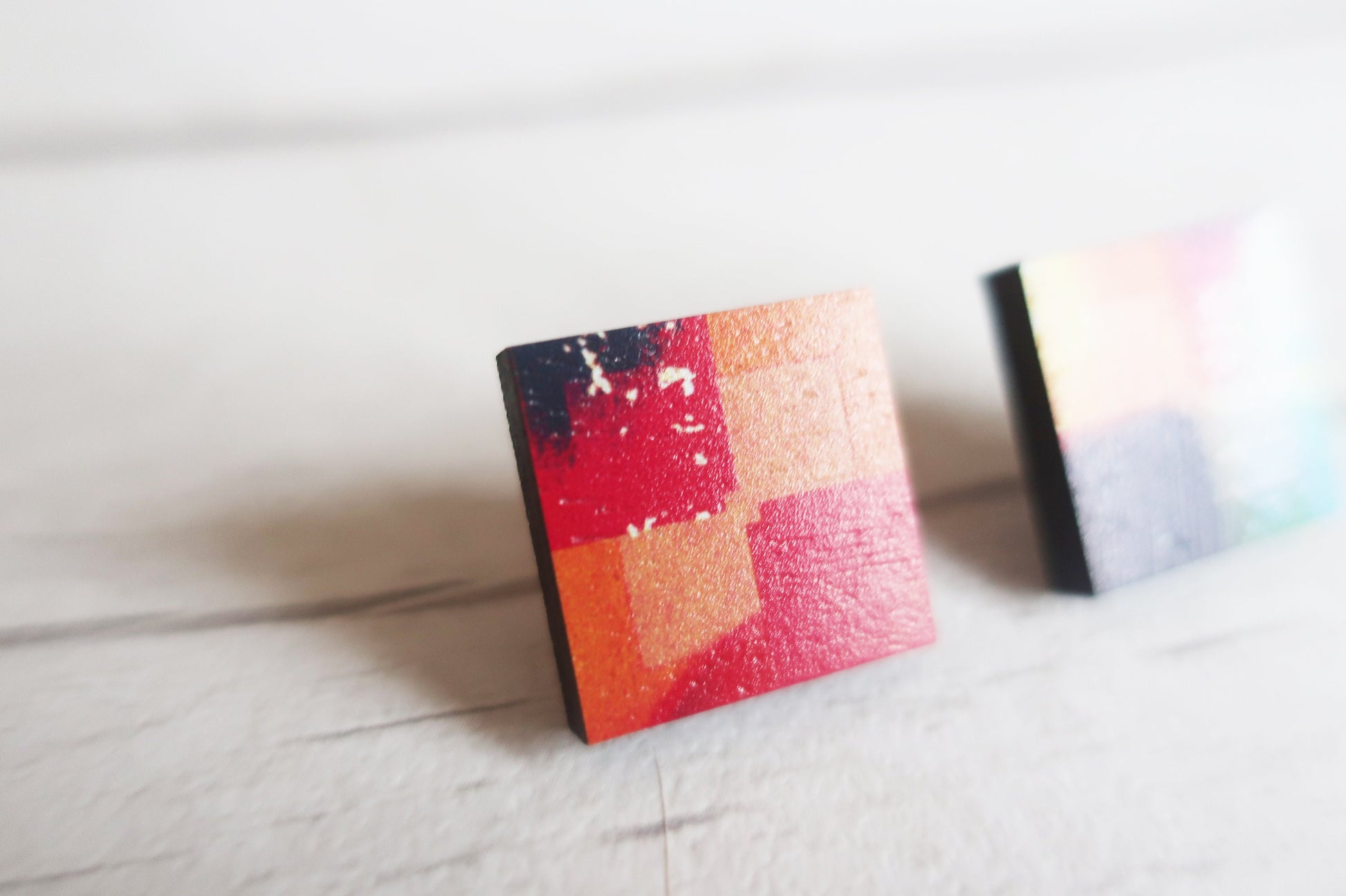 Colorful square earrings on a light surface
