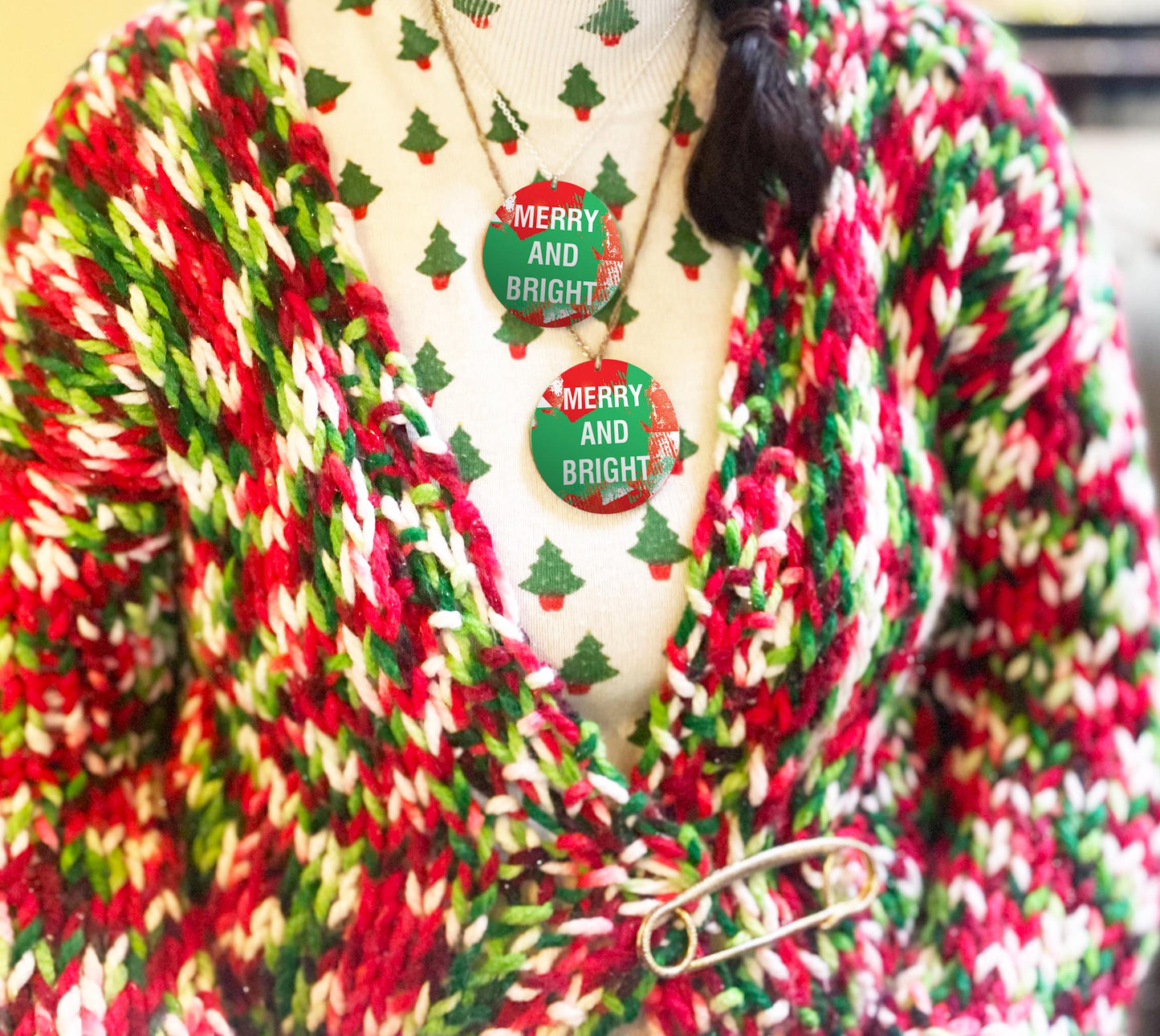 Colorful knitted cardigan with a 'Merry and Bright' necklace on a mannequin.