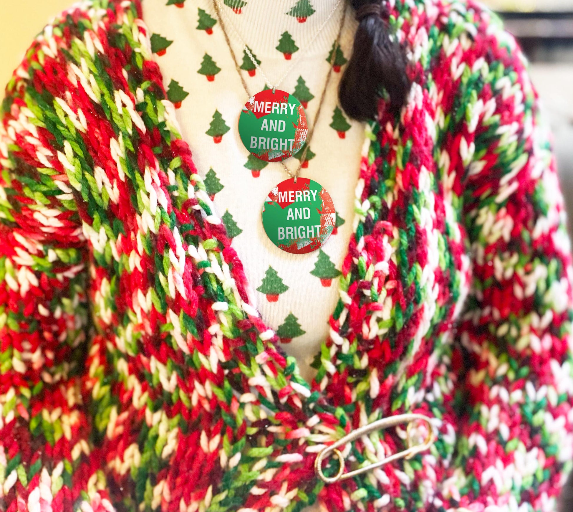 Colorful knitted cardigan with a 'Merry and Bright' necklace on a mannequin.