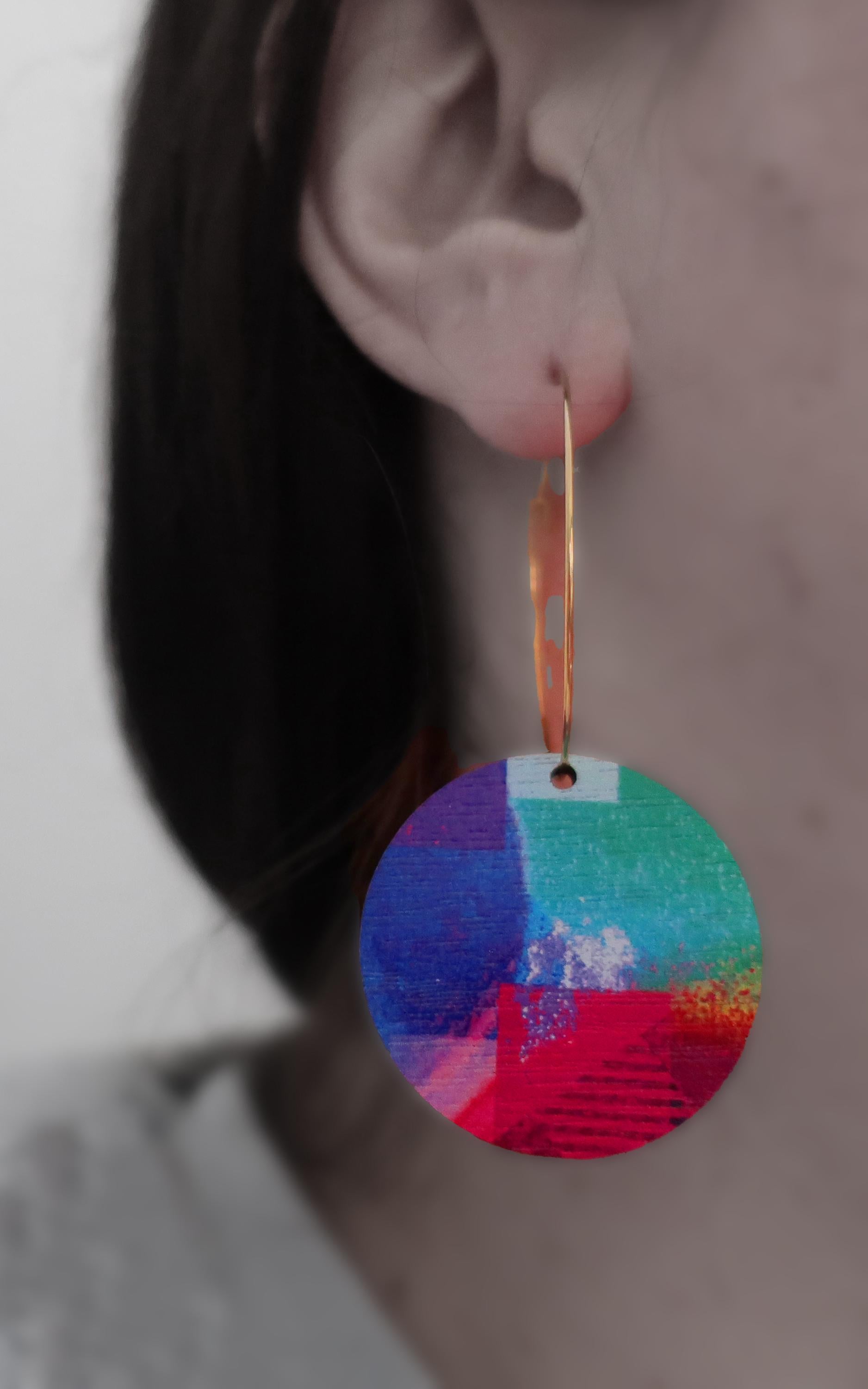 Close-up of a colorful circular earring worn by a person.