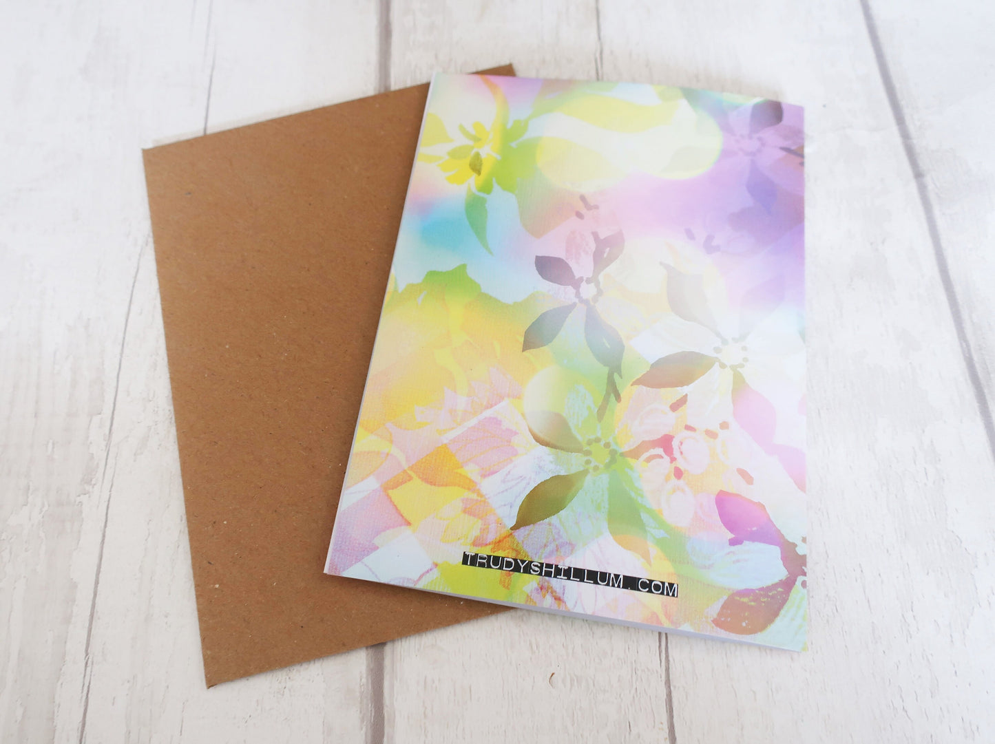 Floral watercolor card and brown envelope on a light wooden surface