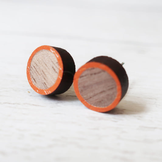 Round wooden earrings with orange and black accents on a white background