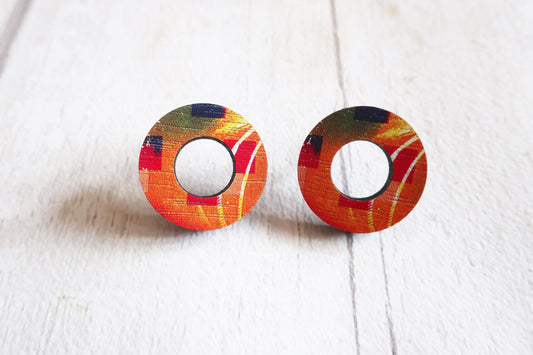 Colorful circular earrings on a white wooden surface