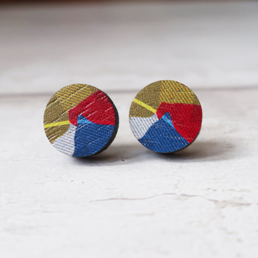 Pair of round earrings with geometric color pattern on a light background