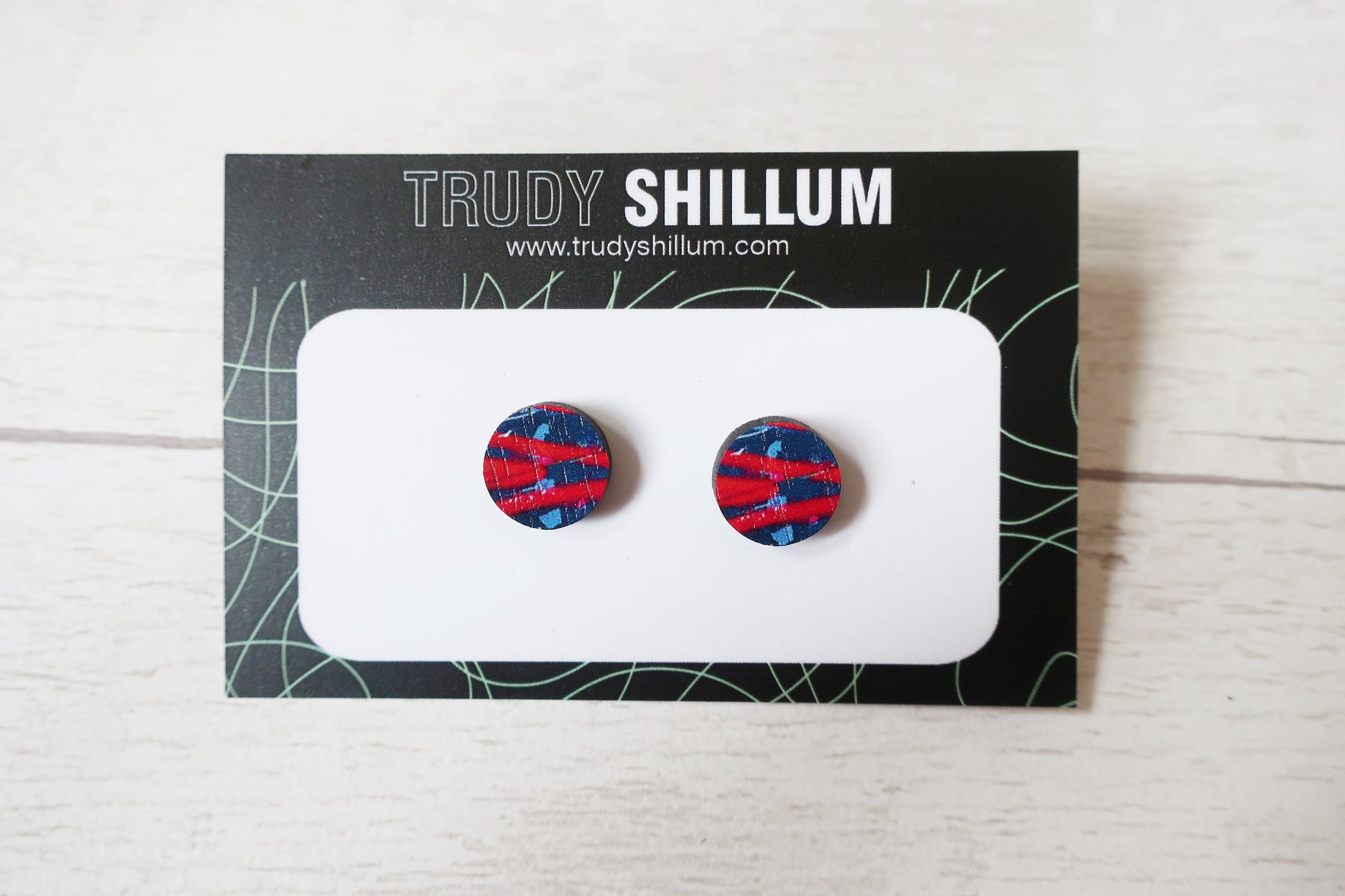 Pair of round earrings with a red, white, and blue pattern on a Trudy Shillum branded card.