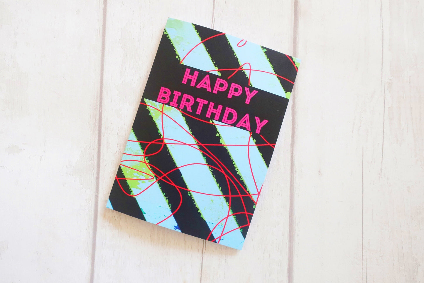 Colorful birthday card with abstract design on a white wooden surface