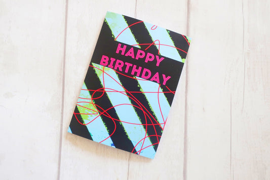 Colorful birthday card with abstract design on a white wooden surface