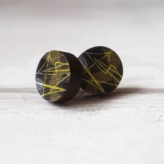 Pair of round earrings with black and yellow pattern on a white background