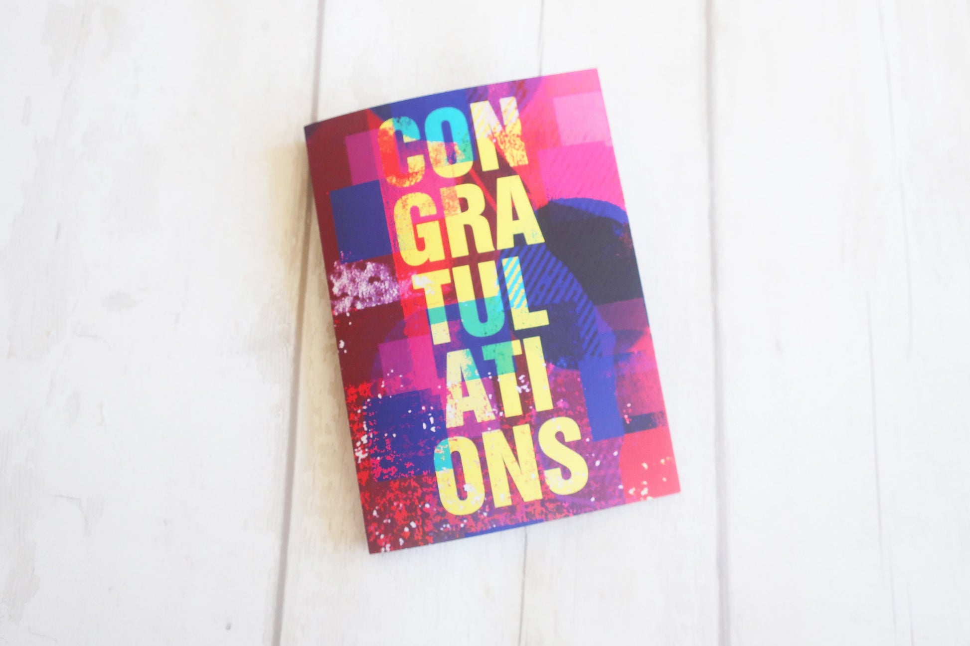 Colorful greeting card with 'Congratulations' text on a white wooden surface