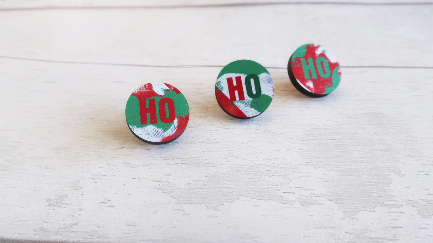 Three circular pin badges with 'HO' design on a light wooden surface