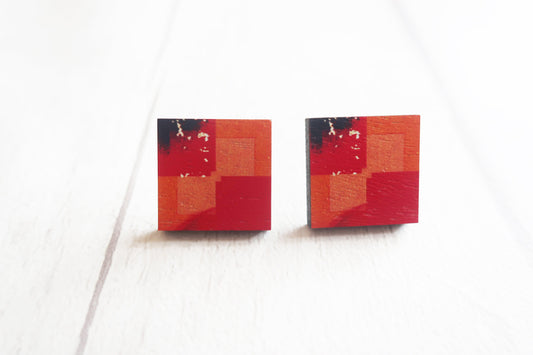 Pair of square earrings with red and black abstract design on a white background