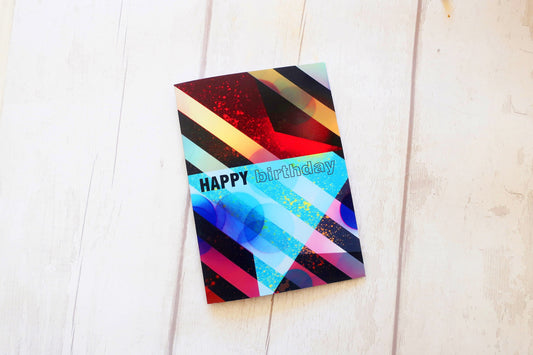 Colorful birthday card with geometric design on a white wooden surface